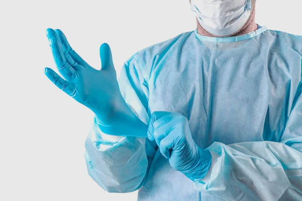 A medic in a protective suit puts on medical gloves. Personal protection for the coronavirus pandemic infection virus covid 19. Protective medical equipment for laboratories, research hospitals