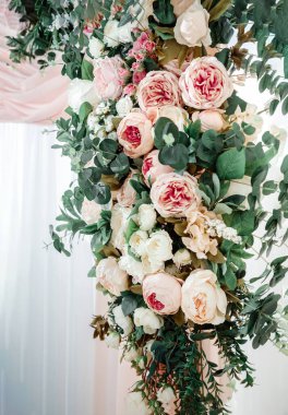 Tören için düğün kemeri, süslü bir çiçek aranjmanı ve kumaşla süslenmiş. Şatafatlı bir etkinlik için gül, şakayık ve okaliptüs dekoru. Çiçekli tatil süslemesi.