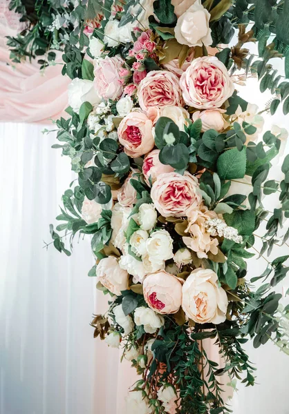 Tören için düğün kemeri, süslü bir çiçek aranjmanı ve kumaşla süslenmiş. Şatafatlı bir etkinlik için gül, şakayık ve okaliptüs dekoru. Çiçekli tatil süslemesi.