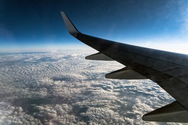 Bulutların üzerinde uçan bir uçağın kanadının pencereden görüntüleme
