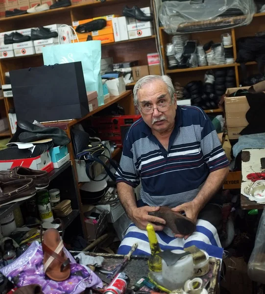Elderly shoemaker works in his workshop — 图库照片
