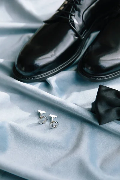 Groom accessories. Shoes, bow tie, and cufflinks. On the blue background.