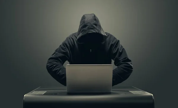 Хакер в маске на ноутбуке — стоковое фото