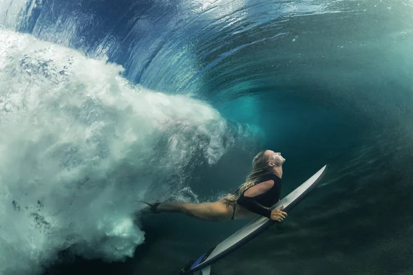 Surfer girl under ocean wave