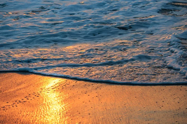 Spiaggia al tramonto con sabbia bagnata arancione e schiuma di mare su di essa — Foto Stock