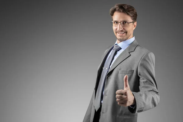 Podnikatel v šedém obleku s úsměvem a palec nahoru — Stock fotografie