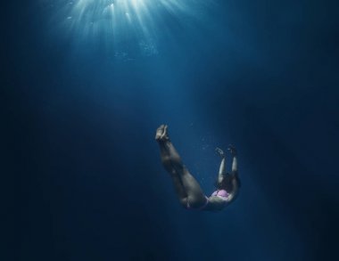 Kız mavi derin su okyanusun karanlık deniz arka plan parlak güneş ışığı ile karşı batan