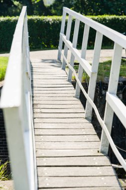 Beyaz ahşap ayak güneşli bir günde dar bir nehir üzerinde köprü