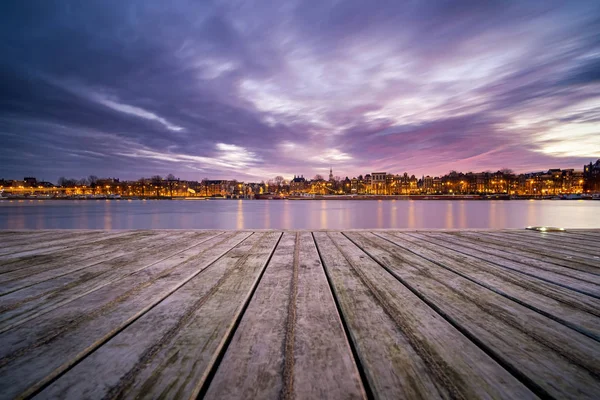 Vista sobre o horizonte de Amsterdã durante o pôr do sol de um molhe — Fotografia de Stock