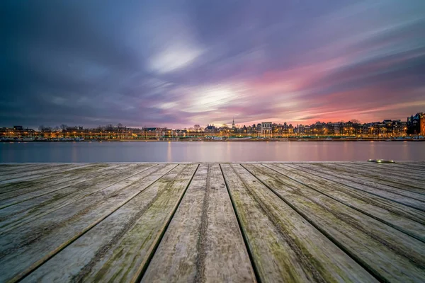 Vista sobre o horizonte de Amsterdã durante o pôr do sol de um molhe — Fotografia de Stock