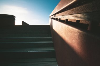 Kum tepelerinde güneş ışığı ve zıt bir gölgeyle aydınlatılmış çelik paslı korkuluklu modern bir kayışın soyut görüntüsü.