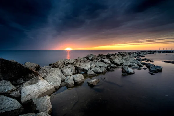 フレヴォランド州のウルクの町の近くにあるIjsselmeerの大きな岩の防波堤は 大きな雲と色の劇的な夕日の間に — ストック写真