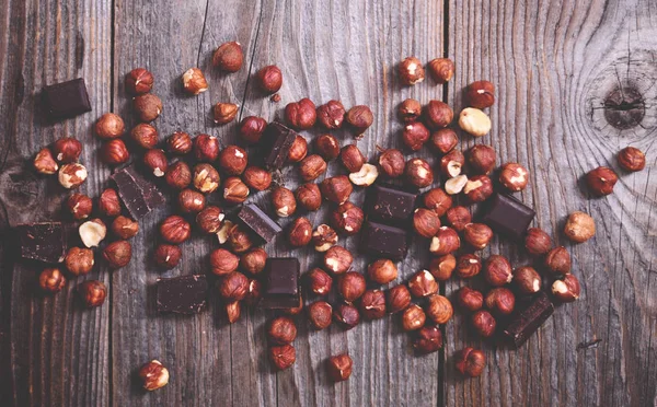 Čerstvé lísky a tmavá čokoláda na dřevěné pozadí — Stock fotografie