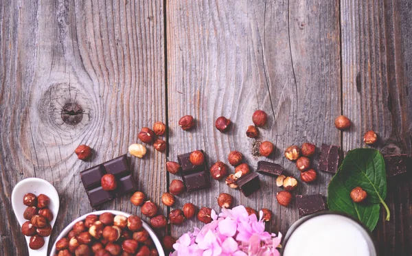 Fresh hazelnut and dark chocolate on wooden background — Stock Photo, Image