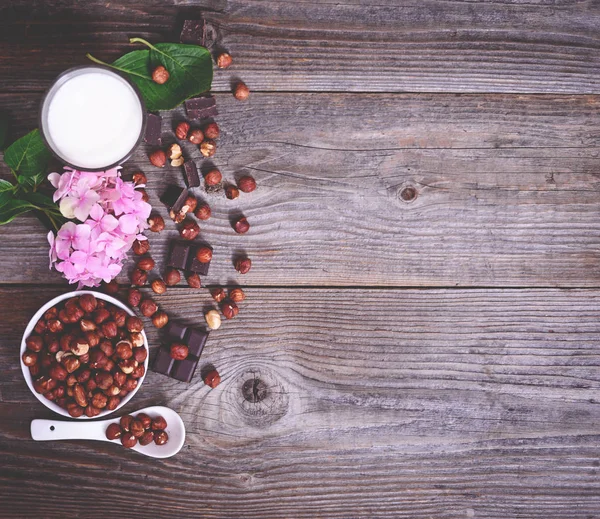 Avellana fresca, leche y chocolate negro sobre mesa de madera — Foto de Stock