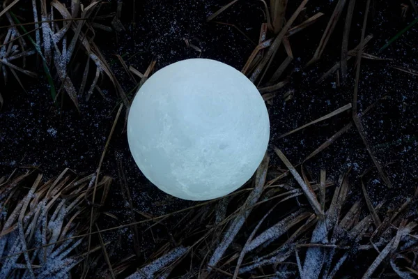 A full moon on the ground during the evening. Lunar model, moon-shaped lamp with moon craters