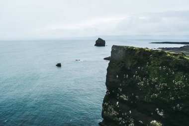 Atlantik okyanusunun mavi suları üzerindeki kayalık İzlanda kayalıklarının bunaltıcı manzarası