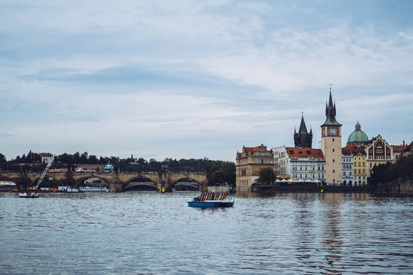 Beautiful architecture of Prague on a calm sunny day over the waters of Vltava river. One of the most popular European travel destinations. Admiring a romantic sunset from a boat.