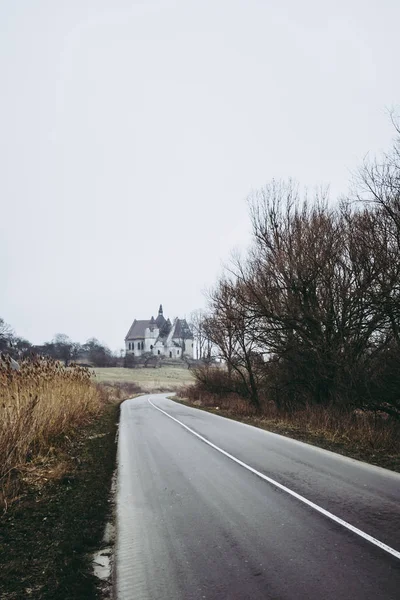 Cores dessaturadas pálidas de uma estrada de aldeia perto de Lviv, Ucrânia. Igreja abandonada em segundo plano. Manhã cinzenta nublada — Fotografia de Stock