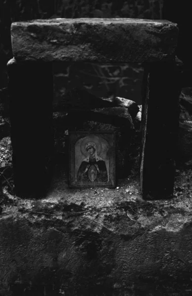 O ícone abandonado da Virgem Maria sob os tijolos que a protegem de ser destruída. Ruínas da antiga igreja perto de Lviv, Ucrânia. Preto e branco — Fotografia de Stock