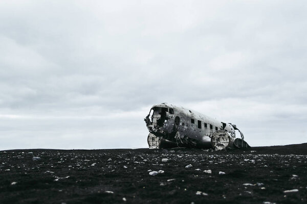 Останки разбитого самолета на черном песчаном пляже в Исландии под тяжелыми серыми облаками
.