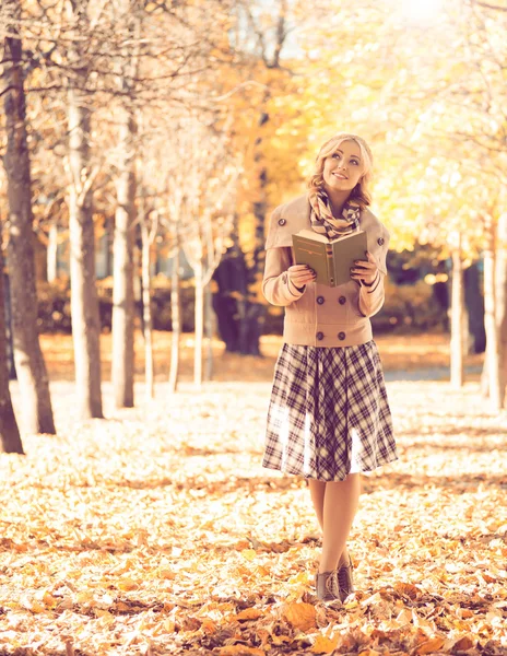 Mulher andando no parque de outono com livro — Fotografia de Stock