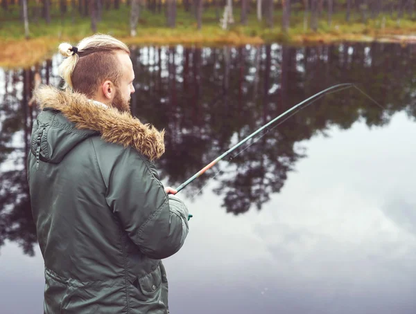 Young man fishing with spinning rod — Stock Photo, Image