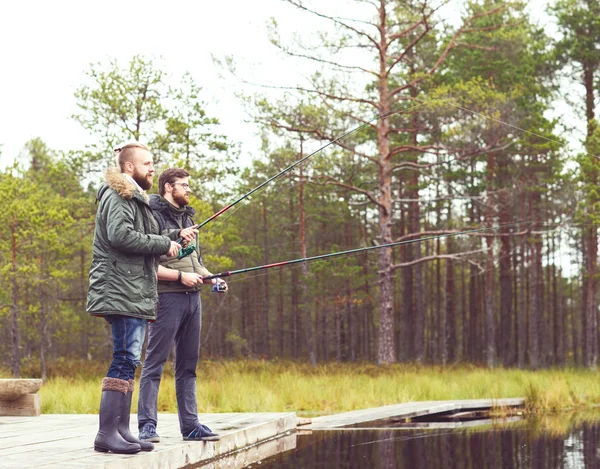 Hombres jóvenes pescando con cañas giratorias —  Fotos de Stock