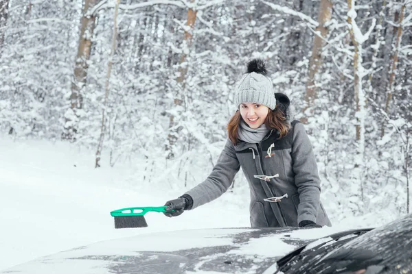 Jovem mulher limpando carro de neve — Fotografia de Stock