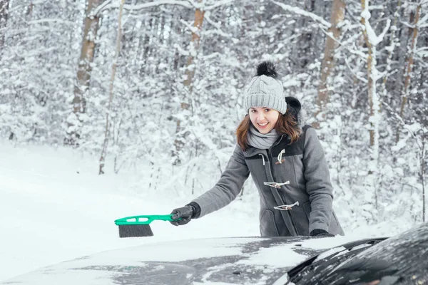 Jonge vrouw auto sneeuw schoonmaken — Stockfoto