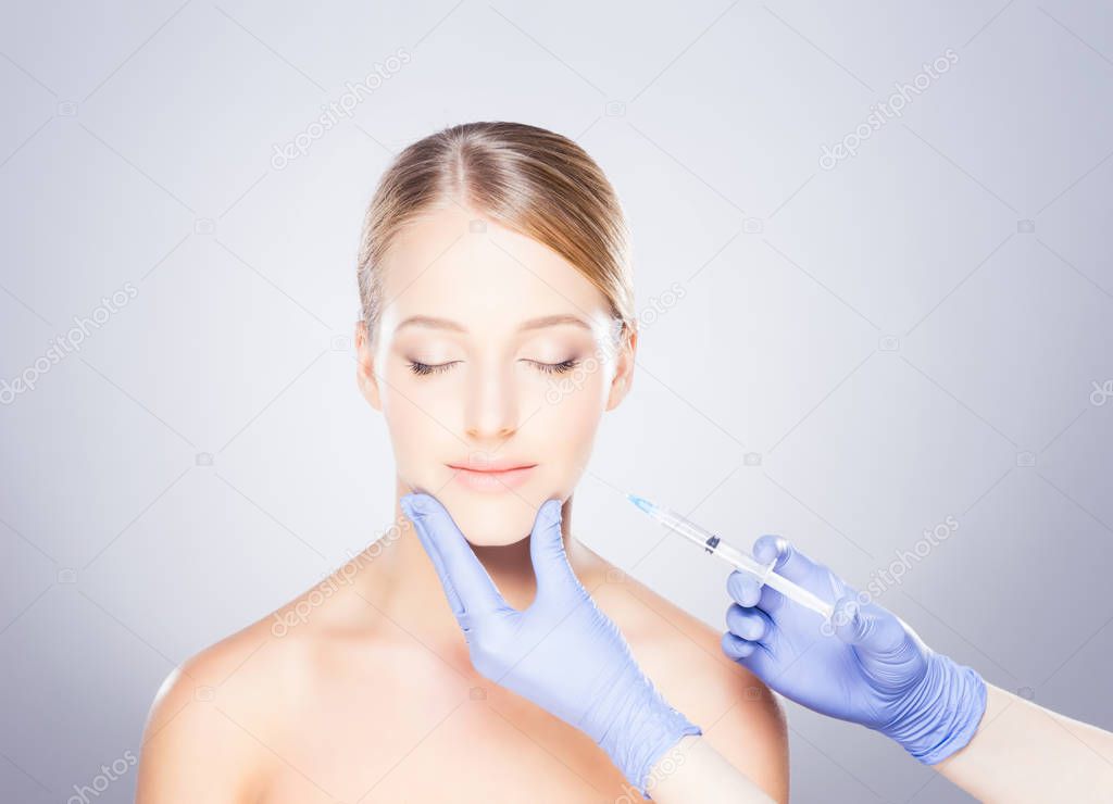 Doctor making injection into face of woman