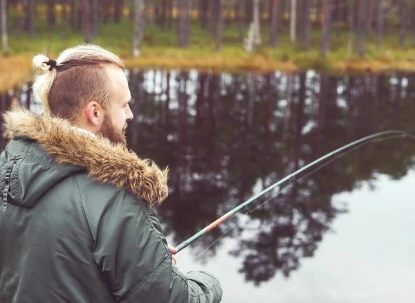 Young man fishing with spinning rod — Stock Photo, Image