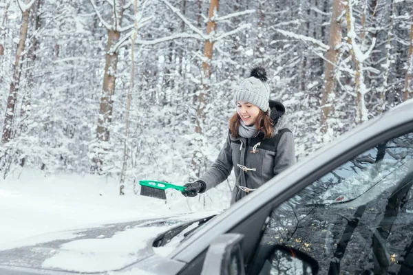Junge Frau reinigt Auto vom Schnee — Stockfoto