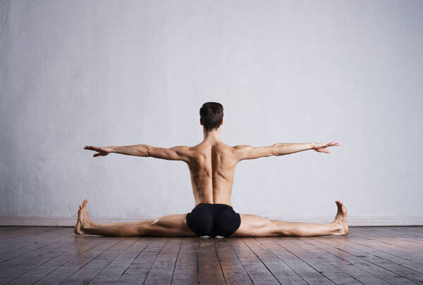 Handsome ballet dancer sitting on split