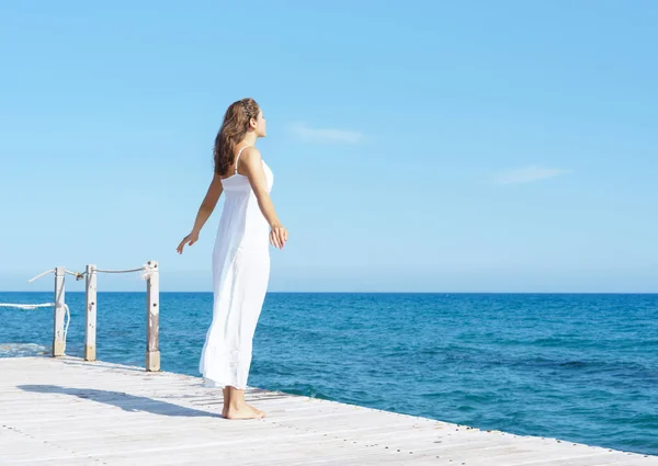 Vrouw in witte jurk op houten pier — Stockfoto