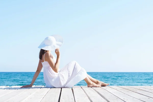 Vrouw in witte jurk op houten pier — Stockfoto