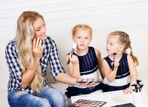 Giovane madre con due belle figlie con una tavolozza di trucco — Foto Stock