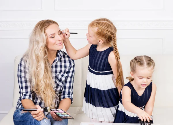 Giovane madre con due belle figlie con una tavolozza di trucco — Foto Stock