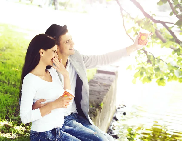 Junges glückliches Paar sitzt im Park — Stockfoto