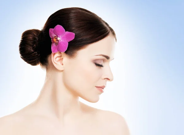 Attraktiv brunett kvinna med orkidé i hår — Stockfoto