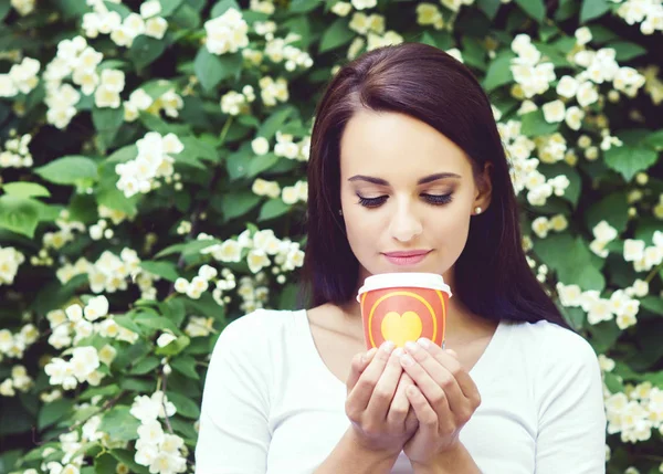 Jonge vrouw genieten van koffie in park — Stockfoto