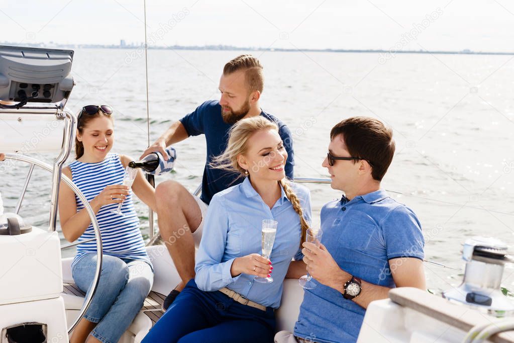 Group of happy friends having a party on a yacht and drinking