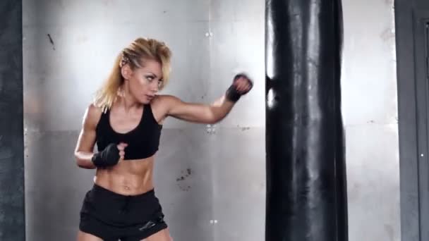 Una mujer hermosa y en forma tiene un entrenamiento de kickboxing. Deporte, salud, concepto . — Vídeo de stock