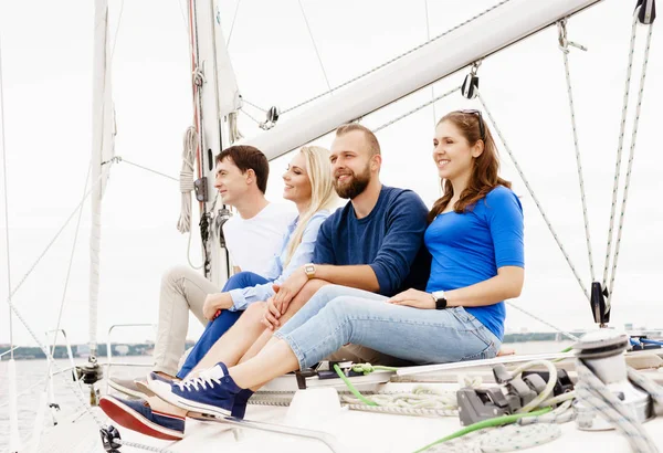 Happy friends sitting together on a deck of a yacht — Stock Photo, Image