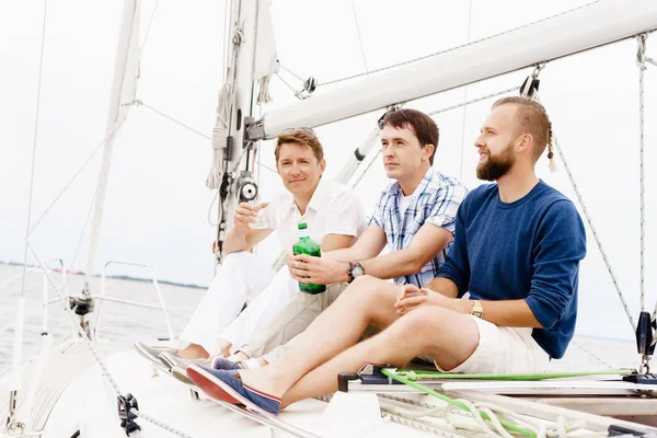 Счастливые друзья сидят вместе на палубе яхты — стоковое фото
