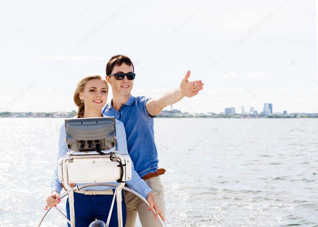 Happy and beautiful young couple relaxing on a yacht