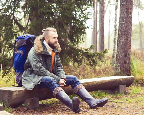 Vousatý muž sedící na log v lese — Stock fotografie