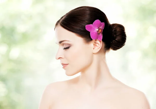 Attractive brunette woman with orchid in hair — Stock Photo, Image