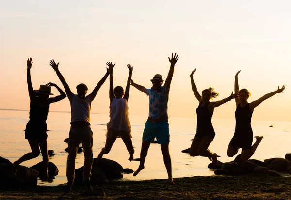Счастливые друзья, прыгающие на морском пляже — стоковое фото
