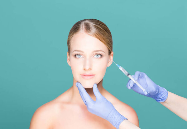 Доктор делает укол женщине в лицо
